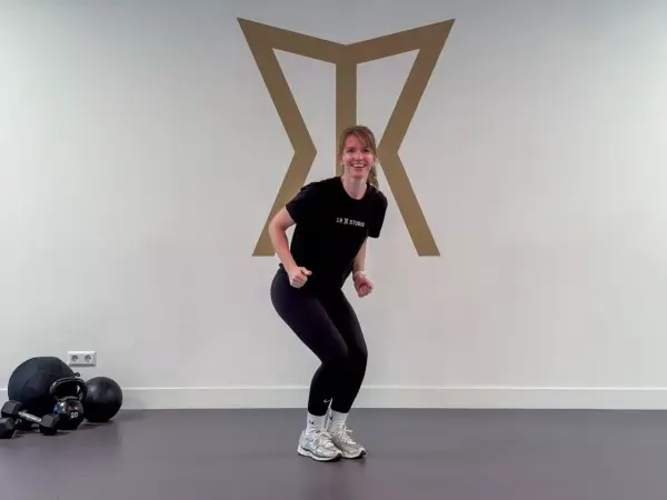 Frau in Sportkleidung macht eine Kniebeuge, bereit für das Skifahren. Krafttraining für die Pisten.